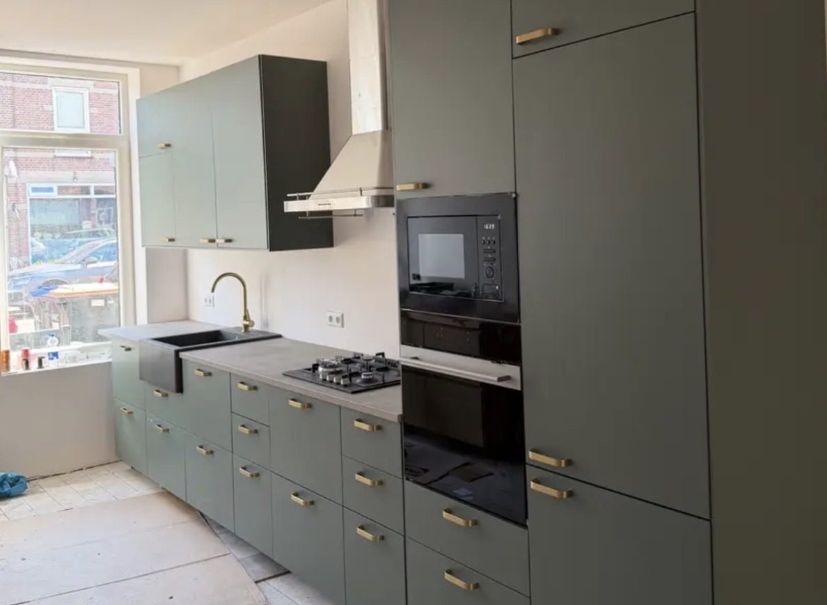 Groene keuken met messing grepen en inbouwapparatuur